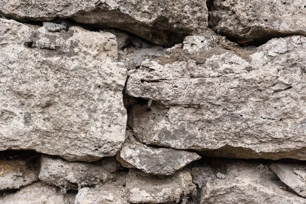 Close-up fundo texturizado é uma parede de pedra natural irregular feita de diferentes pedras sem uma mistura de ligação do tipo cimento. Fundo medieval — Fotografia de Stock