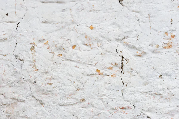 Texturierter Grunge-Hintergrund. volumetrische verputzte Wand mit einer mehrschichtigen rissigen Beschichtung. Orangenchips an der weiß getünchten Wand. Grunge-Textur mit tiefem Muster — Stockfoto