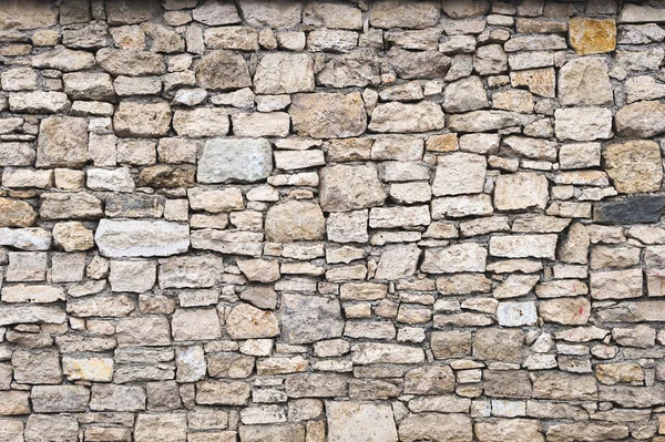 Close-up fundo texturizado é uma parede de pedra natural irregular feita de diferentes pedras sem uma mistura de ligação do tipo cimento. Fundo medieval — Fotografia de Stock