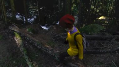 Bir etkin sağlıklı hippi kız fotoğrafçı elleri bir kamera ile ormanda yürür. Düşük anahtar 60 Fps ağır çekim. GoPro 6 Siyah Üç eksenli kolu gimbal sabitleyici ile