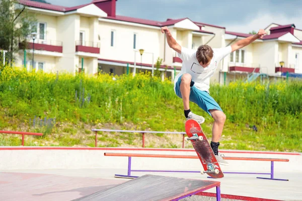 Um menino em um parque de skate fazendo um truque em um skate — Fotografia de Stock