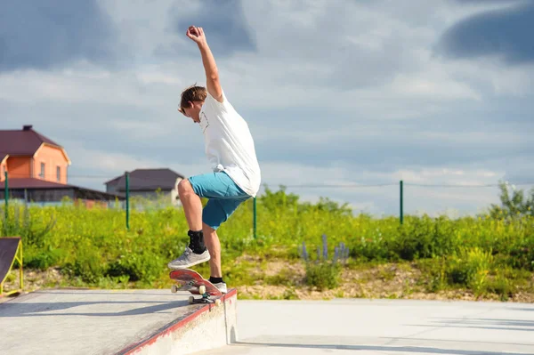 Um menino em um parque de skate fazendo um truque em um skate — Fotografia de Stock