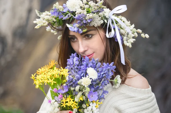 Портрет девушки с венком на голове и букет цветов в руках у водопада — стоковое фото