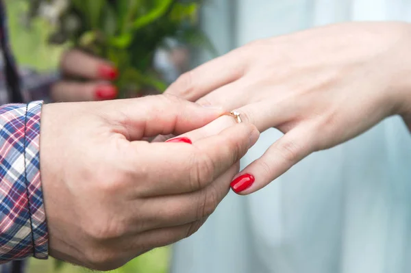 Un homme habille une bague de fiançailles pour une fille sur l'annulaire de sa main gauche — Photo