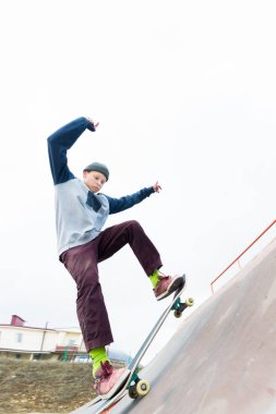 Kapüşonlu sweatshirt ve kot Teen skater bir demiryoluna bir skate Park bir kaykay üzerinde slaytlar