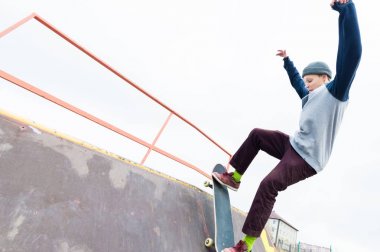Kapüşonlu sweatshirt ve kot Teen skater bir demiryoluna bir skate Park bir kaykay üzerinde slaytlar