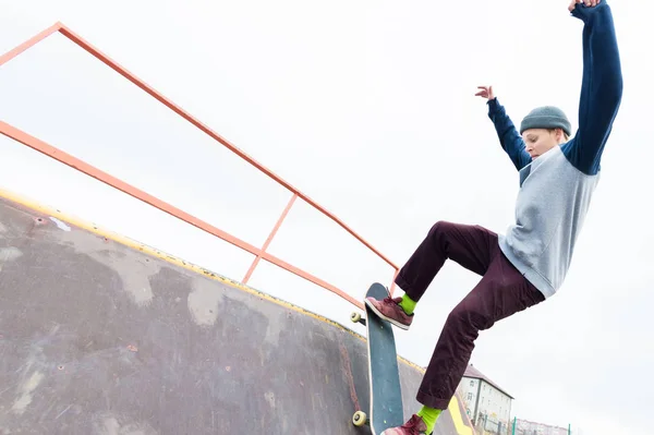 Teen bruslař hoodie mikina a džíny snímky přes zábradlí na skateboardu v skate parku — Stock fotografie