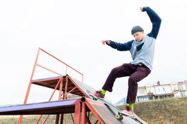 Kapüşonlu sweatshirt ve kot Teen skater bir demiryoluna bir skate Park bir kaykay üzerinde slaytlar