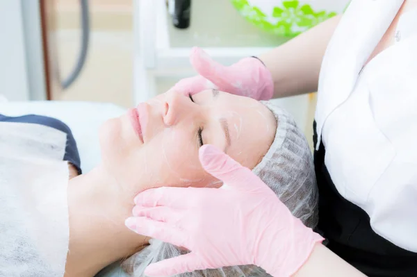 Un primer plano del procedimiento de limpieza en la oficina de cosmetología. Limpieza de la piel con espuma. Hermosa chica en el salón de belleza en el procedimiento de limpieza facial. Trabajo de cosmetólogos . — Foto de Stock