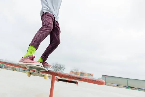 Um close-up de uma perna adolescente de um skatista desliza em um skate ao longo do corrimão no parque de skate. O conceito de seguir em frente em tenra idade. Esportes Adolescentes — Fotografia de Stock