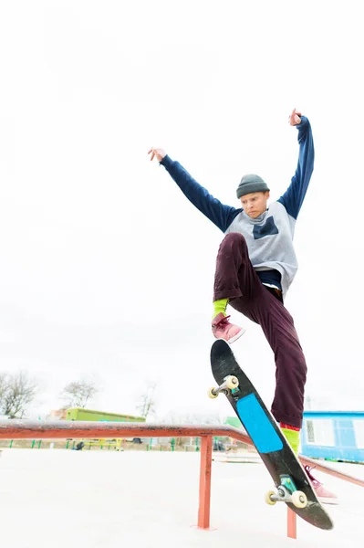 Een jonge tiener, een skateboarder, doet een truc op de leuning in een skatepark. Het concept van jeugd sporten in stedelijke cultuur — Stockfoto