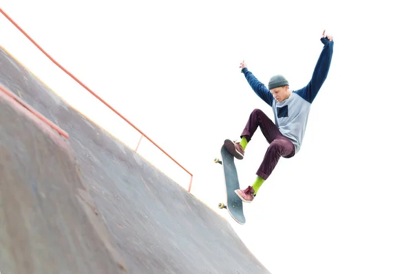 Skateboardista teenagera v cap dělá trik s skok na rampě ve skateparku. Izolované bruslař a rampa na bílém pozadí — Stock fotografie