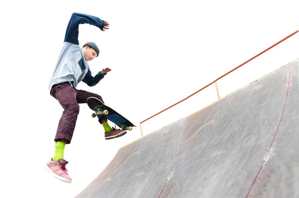 Подросток-скейтбордист в кепке делает трюк с прыжком на рампу в скейтпарке. Изолированный фигурист и рампа на белом фоне — стоковое фото