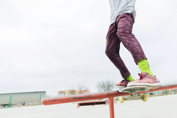 Eine Nahaufnahme eines jugendlichen Beines eines Skateboarders gleitet auf einem Skateboard am Geländer des Skateparks entlang. das Konzept, in jungen Jahren voranzukommen. Jugendsport — Stockfoto
