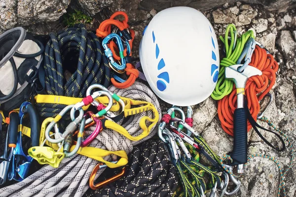 Used climbing equipment - carabiner without scratches, climbing hammer, white helmet and grey,red,green and black rope