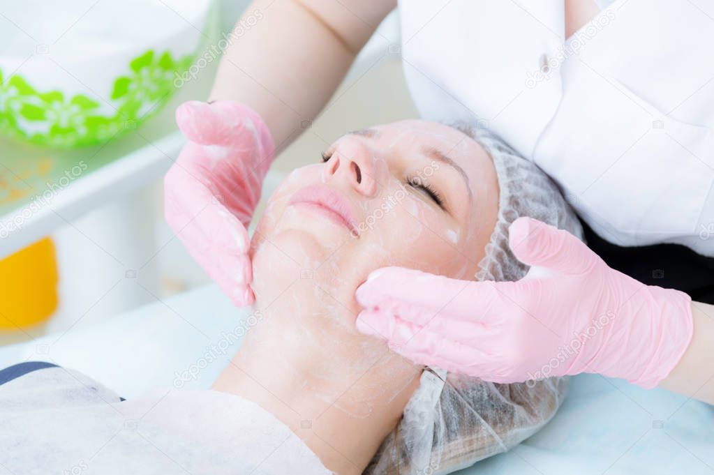 A close-up of the cleaning procedure in the office of cosmetology. Cleaning of the skin with foam. Beautiful girl in beauty salon on facial cleansing procedure. Cosmetologists job.