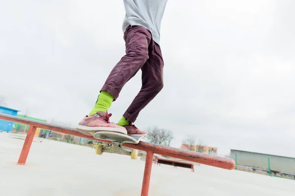 Um close-up de uma perna adolescente de um skatista desliza em um skate ao longo do corrimão no parque de skate. O conceito de seguir em frente em tenra idade. Esportes Adolescentes — Fotografia de Stock