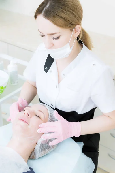 En närbild av rengöringsproceduren i kontoret av kosmetika. Rengöring av huden med skum. Vacker flicka i skönhetssalong på ansiktsbehandling rengöring förfarandet. Kosmetologer jobb. — Stockfoto