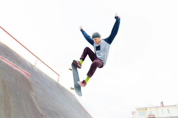 Um adolescente skatista de chapéu faz um truque com um salto na rampa. Um skatista está voando no ar — Fotografia de Stock