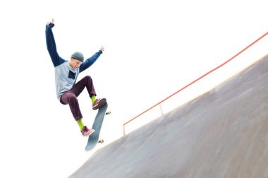 Genç kaykaycı şapkalı bir atlama skatepark rampa ile bir hile yok. İzole patenci ve beyaz zemin üzerine rampa