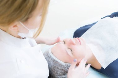 Güzellik Salonu. Tıbbi bir güzellik pembe eldiven close-up bir yüz yapar masaj güzel bir kadının. Kozmetik. Baş ve omuz kapalı gözlü bir kız. Bayan güzellik kavramı ve