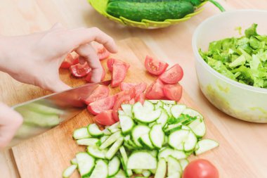 Yakın çekim narin eller çeyrek bir ahşap tahtada evde domates büyük bir bıçakla kesti. Ev mutfak. Sağlıklı beslenme. Vejetaryenlik kavramı