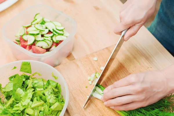 Primer plano de suave hembra manos rebanar en el tablero de madera los tallos de cebollas verdes haciendo ensalada. El concepto de una comida vegetariana saludable y estilo de vida. Hacer comida saludable en casa — Foto de Stock