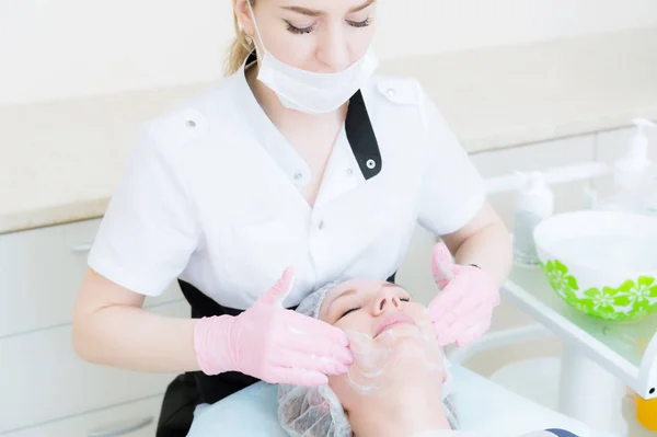 Um close-up do procedimento de limpeza no escritório de cosmetologia. Limpeza da pele com espuma. Menina bonita no salão de beleza no procedimento de limpeza facial. Trabalho de cosmetologistas . — Fotografia de Stock
