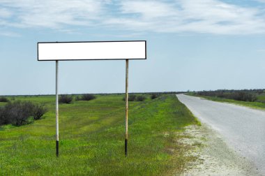 Yeşil çimenler ile çevrili mavi bir lanet ve beyaz bulutlar karşı kırsal bir yol yakınında bir şehir veya köy nüfuslu alan adı için boş bir eski yol işareti