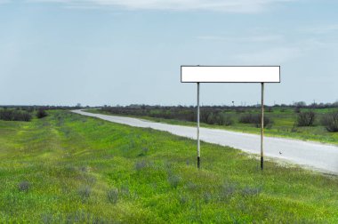 Boş eski yol işareti için bir şehir veya köy adını alan kırsal mavi bir gökyüzü ve beyaz bulutlar tarafından yeşil çim çevrili karşı road yakınındaki doldurulur