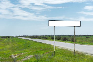 Boş eski yol işareti için bir şehir veya köy adını alan kırsal mavi bir gökyüzü ve beyaz bulutlar tarafından yeşil çim çevrili karşı road yakınındaki doldurulur