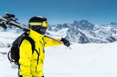 Koruyucu bir kask ve gözlük bir kayakçı büyük bir portresini bir maske ve eşarp ile Kafkasya karla kaplı dağlar omzundan kayaklar olduğunu. Kayak,
