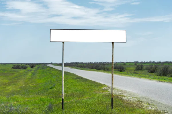 Boş eski yol işareti için bir şehir veya köy adını alan kırsal mavi bir gökyüzü ve beyaz bulutlar tarafından yeşil çim çevrili karşı road yakınındaki doldurulur