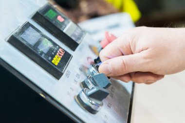 Bir close-up bir el tutar bir çevirmeli anahtar ekipmanlar kontrol panelindeki aletlerimle mans..