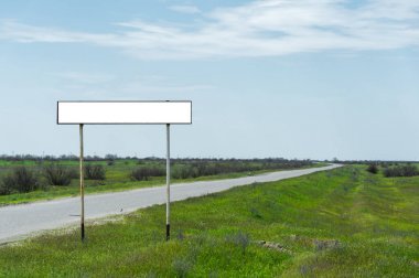 Boş eski yol işareti için bir şehir veya köy adını alan kırsal mavi bir gökyüzü ve beyaz bulutlar tarafından yeşil çim çevrili karşı road yakınındaki doldurulur
