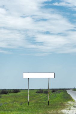 Boş eski yol işareti için bir şehir veya köy adını alan kırsal mavi bir gökyüzü ve beyaz bulutlar tarafından yeşil çim çevrili karşı road yakınındaki doldurulur