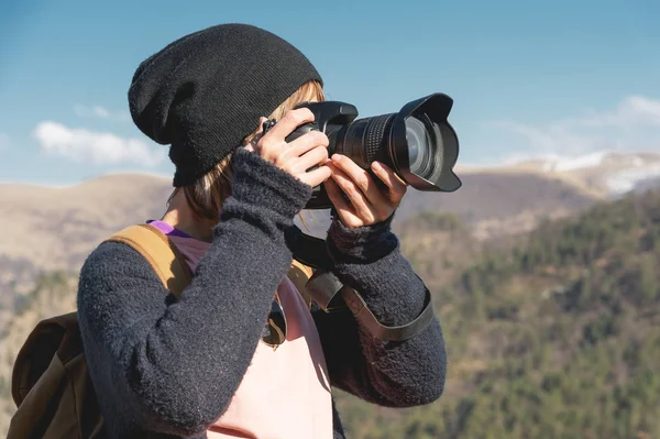 Крупним планом портрет блондинки з цифровою фотокамерою SLR в горах. Стильний фрілансерський фотограф з рюкзаком у гірськолижній поїздці — стокове фото