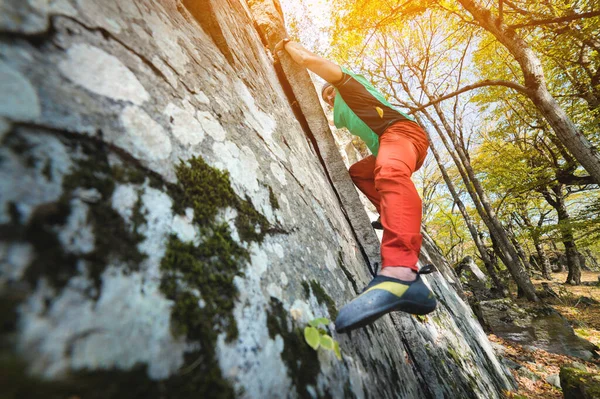 En friåldrig manlig klättrare hänger på en bergvägg i en skog i bergen. Begreppet vuxensport — Stockfoto