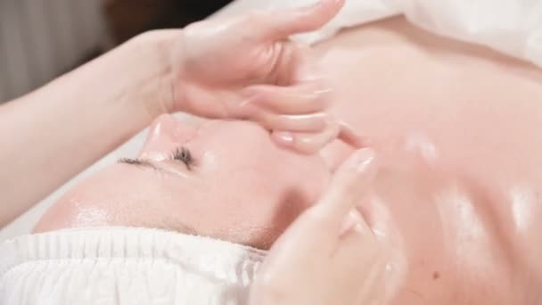 Kapalı Spa yüz masajı. Profesyonel masaj terapisti çekici bir spa salonu müşterisine yüz masajı yapıyor. — Stok video