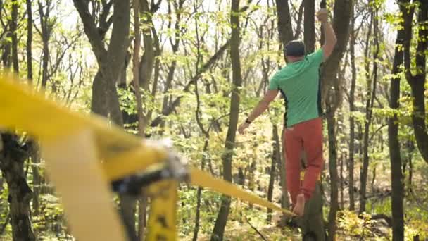 Ein schlaffer Mann mit Bart in Sportbekleidung balanciert auf der Slackline. das Konzept der sportlichen Betätigung im Alter von 50 Jahren — Stockvideo