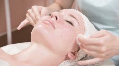 Girl beautician in a mask and gloves makes a salubrious facial massage to an attractive woman. New generation cosmetology massage