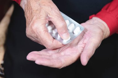 Yaşlı bir kadının elleri yakın plan. Yaşlı kadın kullanmadan önce tabletleri açar.