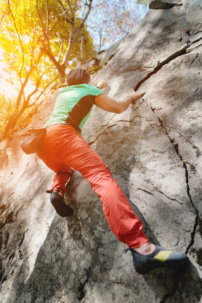 A free aged male climber hangs on a rock wall in a forest in the mountains. Mature Sports Concept — Stock Photo, Image