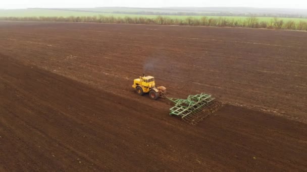 Vue aérienne d'un puissant tracteur jaune avec un grand effort sur le crochet effectuant le labour pour semer des cultures d'hiver avec un cultivateur à disque à l'automne 