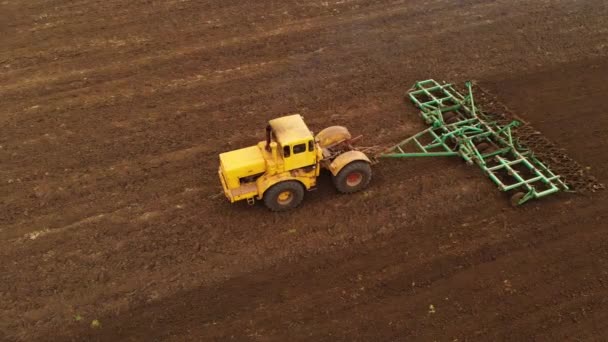 Vue aérienne d'un puissant tracteur jaune avec un grand effort sur le crochet effectuant le labour pour semer des cultures d'hiver avec un cultivateur à disque à l'automne 