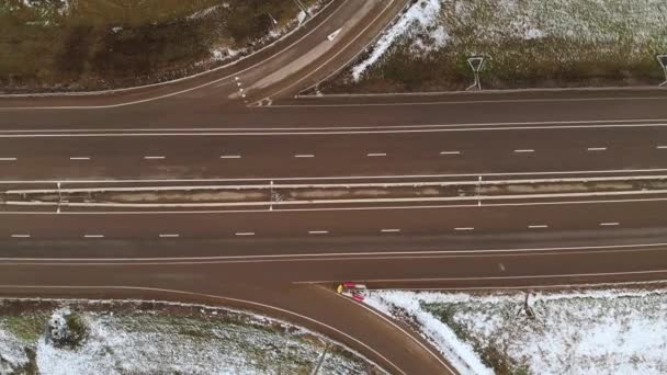 Zdjęcie z lotu ptaka z widokiem na samochody osobowe i ciężarowe poruszające się na zimowym skrzyżowaniu z dużym skrzyżowaniem dróg. Bezzałogowy widok ruchu samochodowego na autostradzie na przedmieściach w zimie. Karuzela na skrzyżowaniu — Wideo stockowe