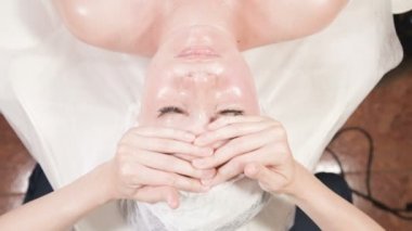 Kapalı Spa yüz masajı. Profesyonel masaj terapisti çekici bir spa salonu müşterisine yüz masajı yapıyor.