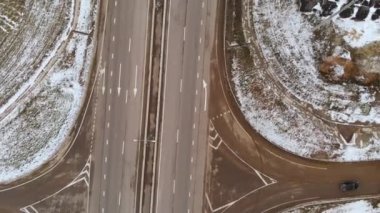 Kış kavşağında büyük bir kavşakla hareket eden araba ve kamyonların hava görüntüsü. Kışın banliyöde bir otoyolda insansız araba trafiği. Kavşaktaki kavşak.