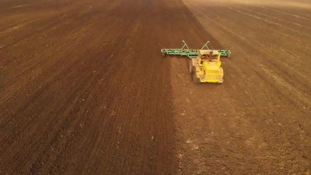 Luchtfoto van een krachtige gele trekker met grote inspanning op de haak uitvoeren ploegen tillage voor het zaaien van wintergewassen met een schijf cultivator in de herfst — Stockvideo