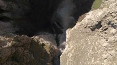 Kafkasya 'daki dik bir uçurumdan devasa bir şelalenin havadan görünüşü. Dağlarda geniş bir su akıntısına yakın çekim. Kafkas İzlanda